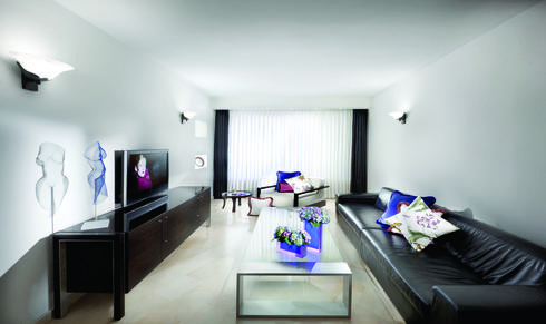 חדר מגורים בעיצוב אלגנטי ומוקפד, המשלב כתמי צבע בפריטי טקסטיל ובחפצי נוי. צילום: אלעד גונן